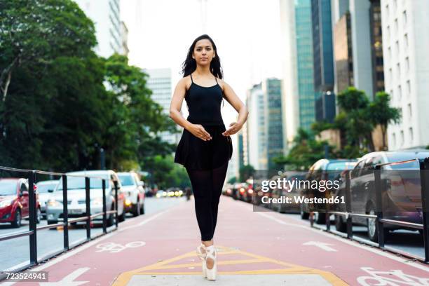 brazil, sao paulo, ballet dancer standing on tiptoes on bicycle lane - urban ballet stockfoto's en -beelden