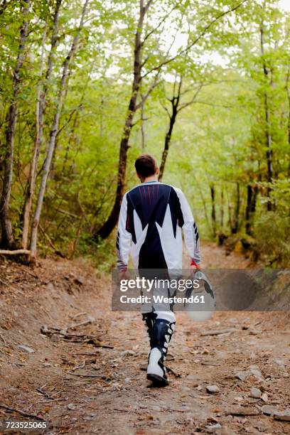 biker wlaking on forest path, rear view - motocross stock photos et images de collection