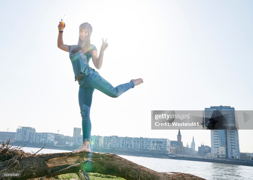 Germany, Cologne, happy young woman with beer bottle at River Rhine