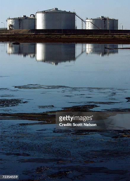 Kuwaiti oil production tanks are reflected in a lake of spilled oil at the Burgan oil field January 13, 2003 in Central Kuwait. The oil field, the...