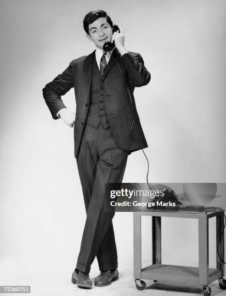 1950s: Man talking on telephone while standing.