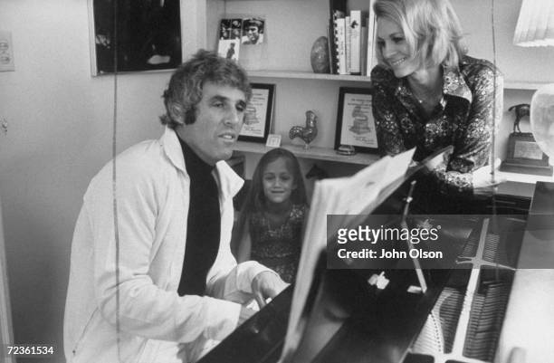 Composer Burt Bacharach Jr. Playing the piano while his actress wife Angie Dickinson and daughter watch and listen.