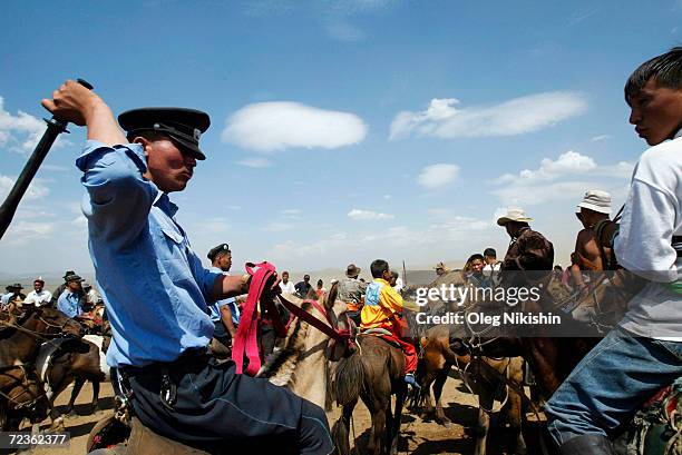 Mongolian policeman controls a crowd after the finish of a horse race on the second day of the Nadam festival July 12, 2003 South of Ulan Bator,...