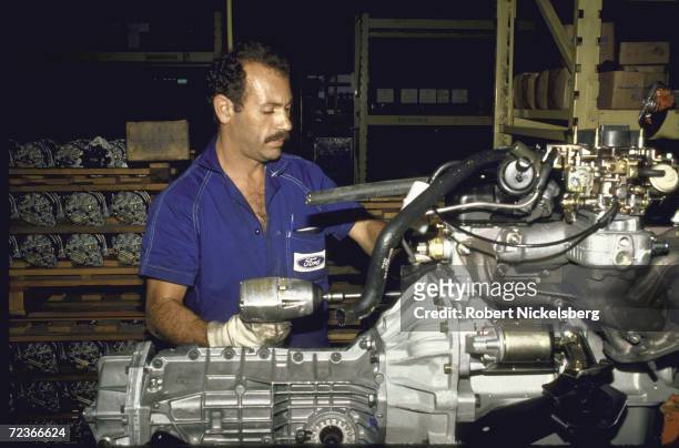 Worker wearing ford logo adorned shirt, working on auto parts in Ford Motor plant , Sao Bernardo de Campo.