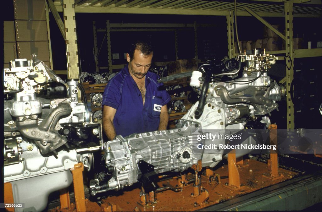 Worker wearing Ford logo adorned shirt working on auto