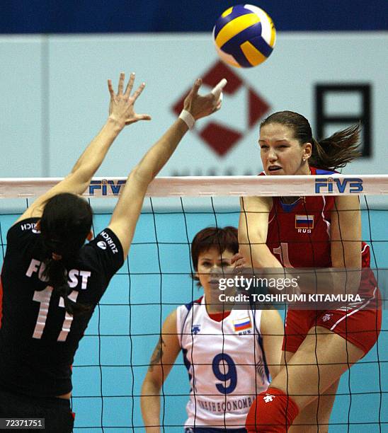 Maria Borodakova of Russia spikes a ball past a block by German Christiane Furst as Russia's Svetlana Kryuchkova looks on during their Pool B match...