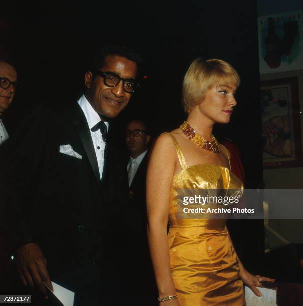 American singer and actor Sammy Davis Jr. Wearing a tuxedo and his fiancee, Swedish actress May Britt, wearing a gold evening gown to the Thalians...
