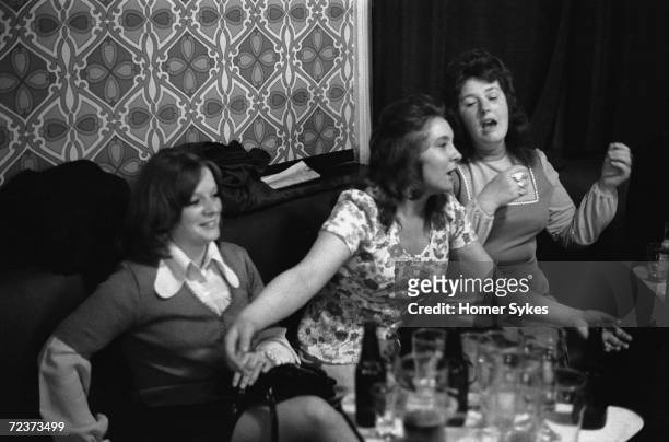 Saturday night out at the Byker & St. Peters Working Men's Social Club in Newcastle Upon Tyne, 1973. Three young women have a singsong at a table...