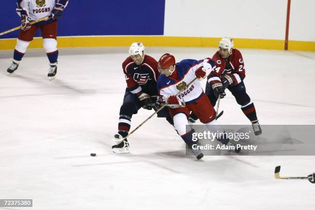 Alexei Yashin of Russia tries to maintain control of the puck with Brian Rolston, left, and Chris Chelios of the USA defending him during men's...