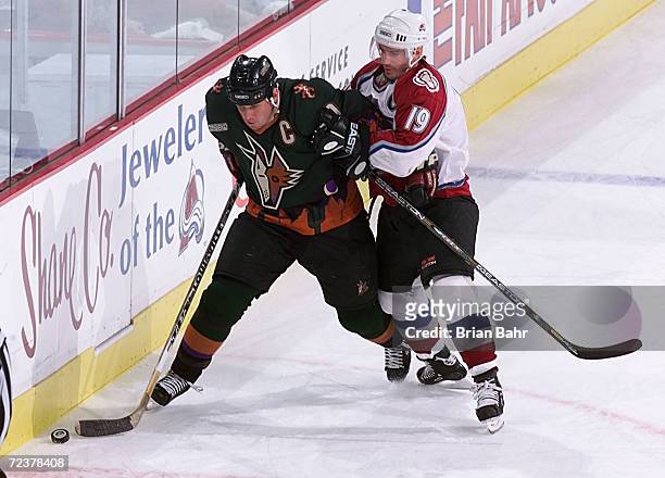 Joe Sakic of the Colorado Avalanche holds back Jeremy Roenick of the Phoenix Coyotes in the first period during game five of the first round of...