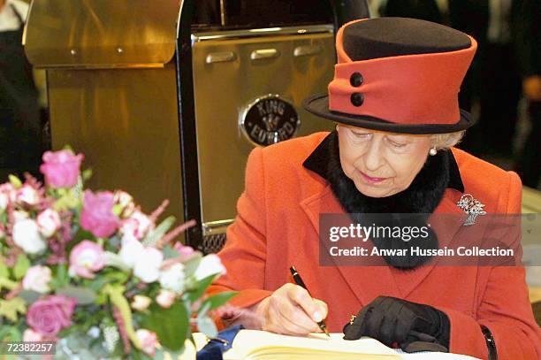 Queen Elizabeth II signs the visitors book as she visits Queen's Square where she met various members of the town and council as they prepare to...