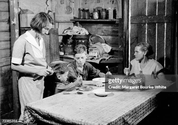 Poor white family having dinner in their rundown Okefenokee Swamp shack.