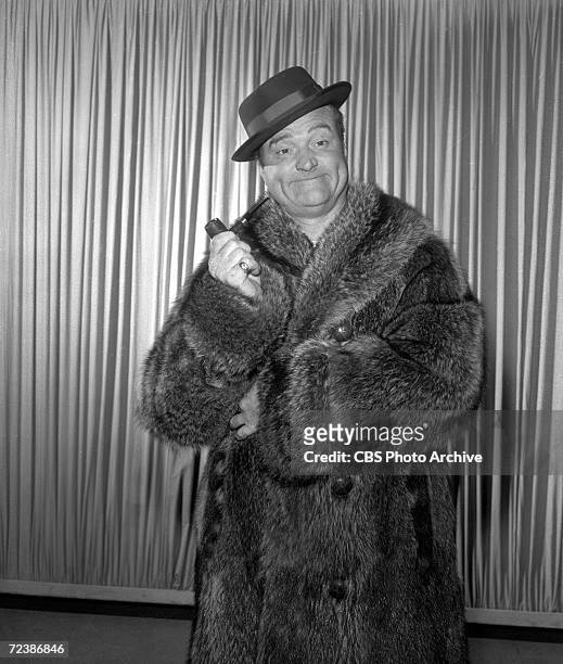 Promotional portrait of American comedian and actor Red Skelton , dressed in a fur coat and porkpie hat, a pipe in his hand, as he poses in support...