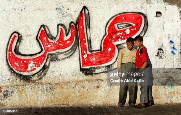 Palestinian boys stand next to a wall painted by an arabic word means Hamas, during an Israeli military incursion November 3, 2006 in Beit Hanun, the...