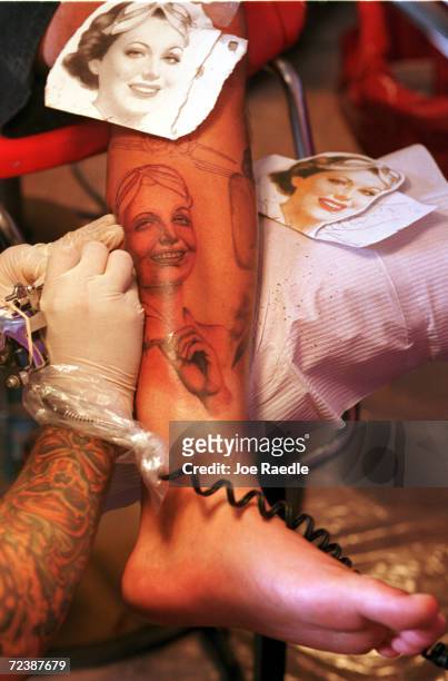 Bobby Sanchez has a pinup girl applied to his leg by Manuel Vega June 9, 2000 at the Texas Tattoo Jam in El Paso, Texas. The event features tattoo...