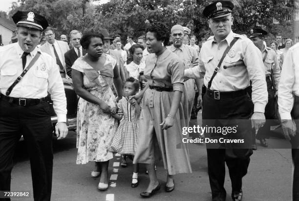 Police escorting African American mothers with grade school kids past jeering mob of demonstrators after the desegregation of the school.