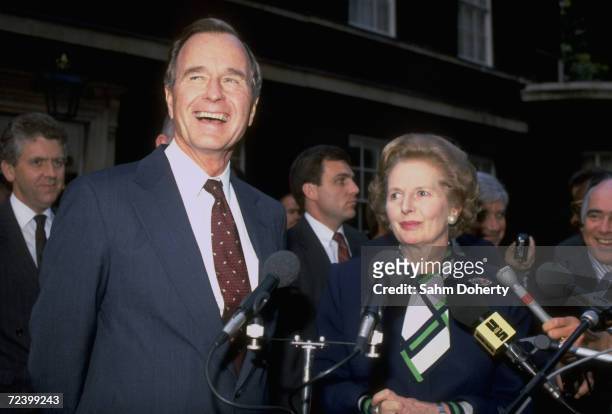 Vice-President George Bush and British Prime Minister Margaret Thatcher speaking into microphones at press conference.