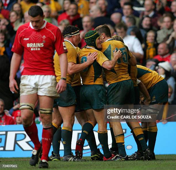 Cardiff, UNITED KINGDOM: The Australian team celebrates player Chris Latham's try as Wales' Ian Evans looks down during their rugby union...