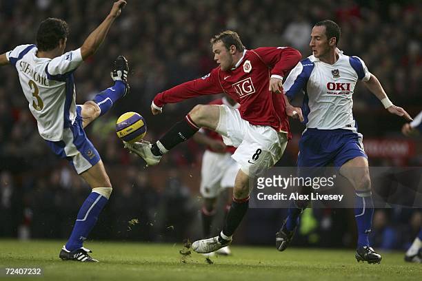 Wayne Rooney of Manchester United is challenged for the ball by Dejan Stefanovic and Andy O?Brien of Portsmouth during the Barclays Premiership match...