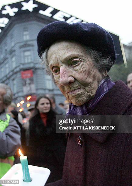 An elderly Hungarian woman holds a candle in front of the House of Terror, former headquarters of the communist secret police which has been...