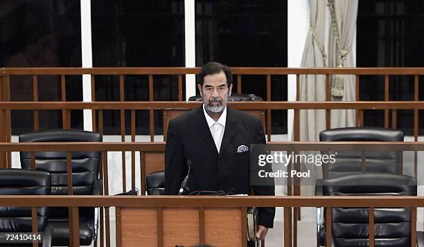 Former Iraqi President Saddam Hussein stands as he receives his guilty verdict during his trial in the fortified 'green zone', on November 5, 2006 in...