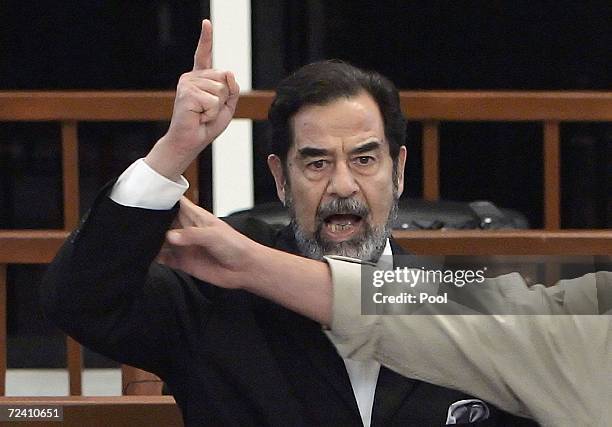 Former Iraqi President Saddam Hussein is held by a court bailiff during his trial in the fortified 'green zone', on November 5, 2006 in Baghdad,...