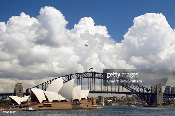 Sydney Opera House and Sydney Harbour Bridge with small plane flying over, Australia.