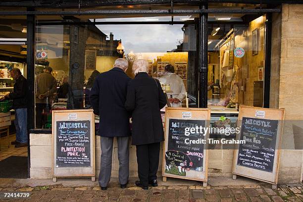 Couple browse the window of a butcher's shop at Burford in the Cotswolds, United Kingdom.