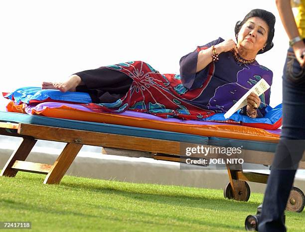 Former Philippines first lady Imelda Marcos arranges her necklace for a photo shoot beside the bayside pool of a top hotel in Manila, 06 November...