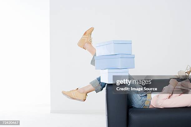 woman on sofa with shoe boxes - schoenendoos stockfoto's en -beelden