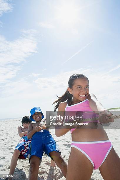 children playing tug of war - young girl swimsuit stockfoto's en -beelden