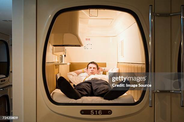 businessman in a capsule hotel - capsule hotel stock pictures, royalty-free photos & images