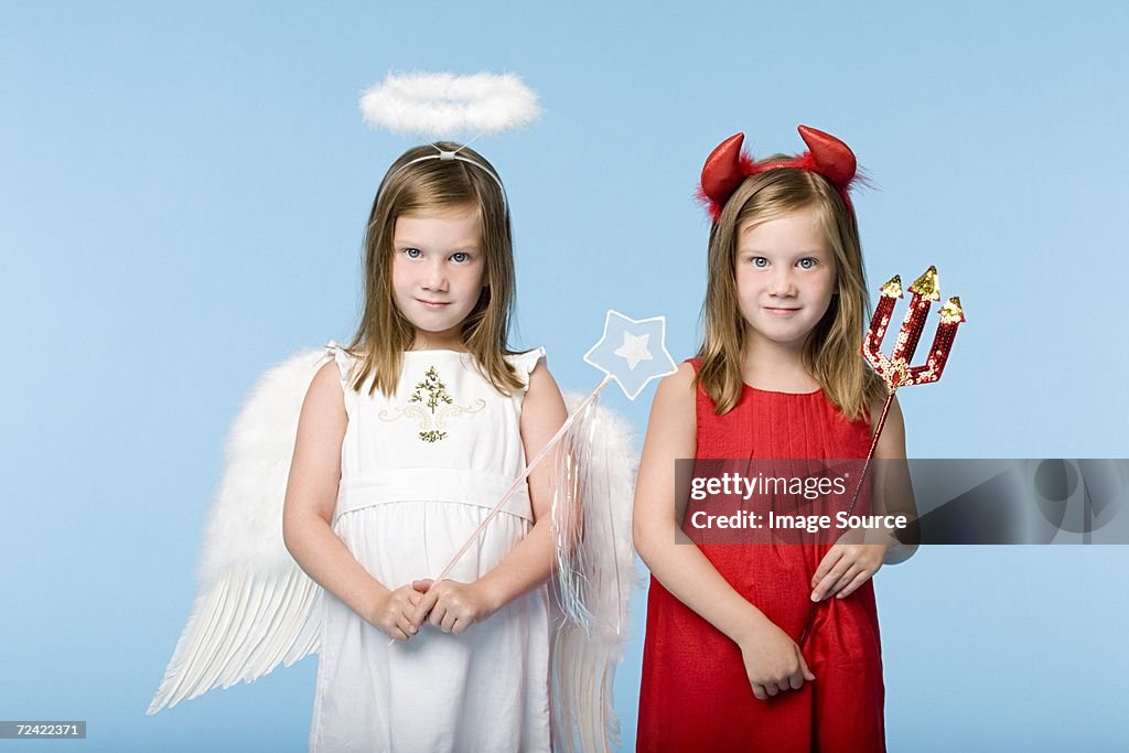 Twin girls dressed as an angel and devil