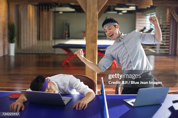 young businessmen using laptops on table tennis table - funny ping pong stock pictures, royalty-free photos & images