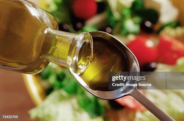 olive oil pouring on to a spoon - olijfolie stockfoto's en -beelden