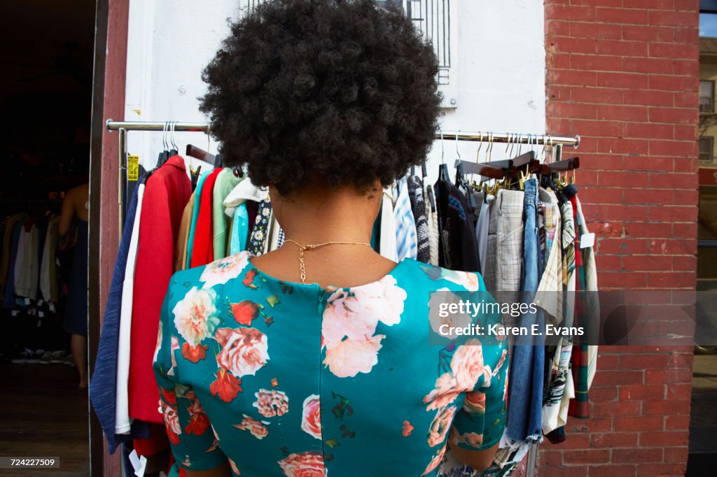 Rear view of young female fashion blogger with afro hair looking at vintage clothes rail, New York, USA