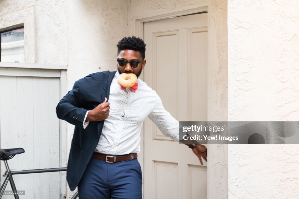Young businessman eating doughnut and closing front door