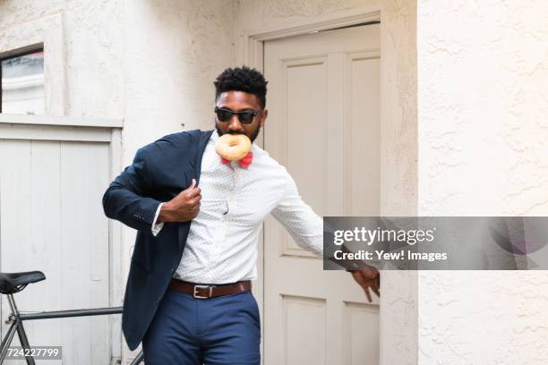 young businessman eating doughnut and closing front door - top priority stock pictures, royalty-free photos & images