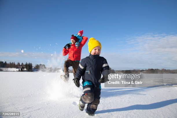father and two sons fooling around, running through snow covered landscape - finlândia - fotografias e filmes do acervo