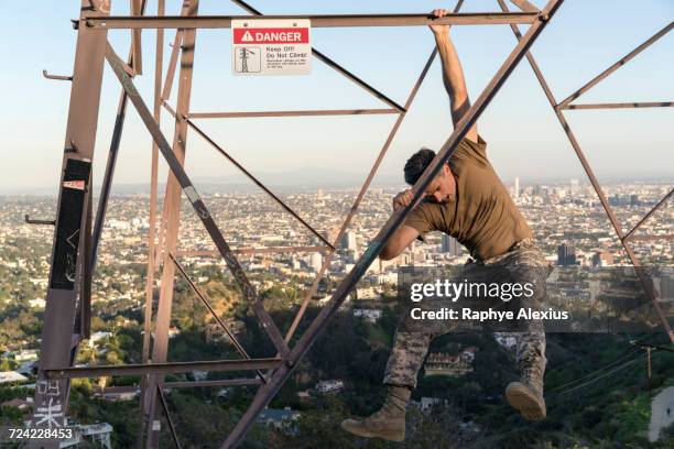 soldier wearing combat clothing dangling from electricity pylon, runyon canyon, los angeles, california, usa - runyon canyon stock pictures, royalty-free photos & images