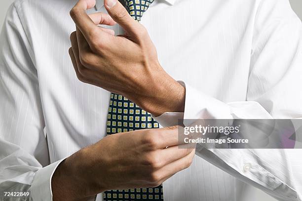 man buttoning cuff of his shirt - buttoning shirt stockfoto's en -beelden