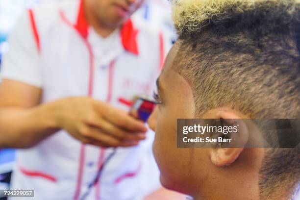 hairdresser cutting teenage boys hair in barbershop - teenage boy shave imagens e fotografias de stock