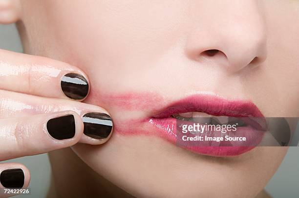 woman smearing lipstick on face - lipstick smudge imagens e fotografias de stock