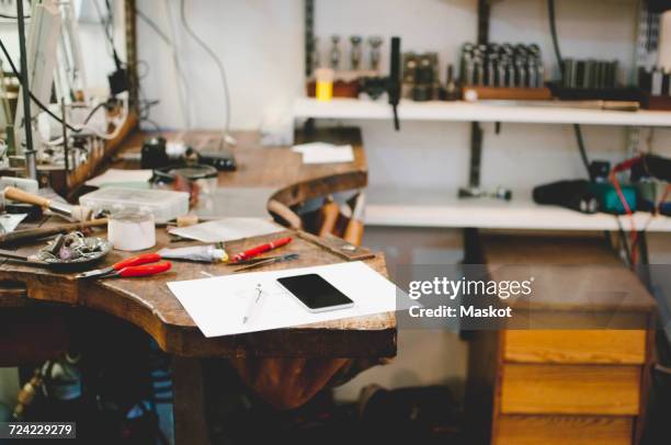 mobile phone and document on workbench in jewelry workshop - établi photos et images de collection