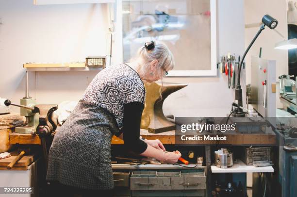 rear view of senior woman holding drill bit in workshop - drawer bildbanksfoton och bilder