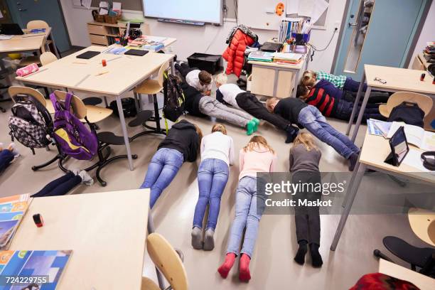 high angle view of junior high students in plank position at classroom - child yoga elevated view stock pictures, royalty-free photos & images