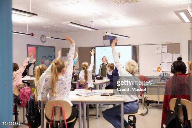 teacher looking at students with arms raised in classroom - sweden school stock pictures, royalty-free photos & images