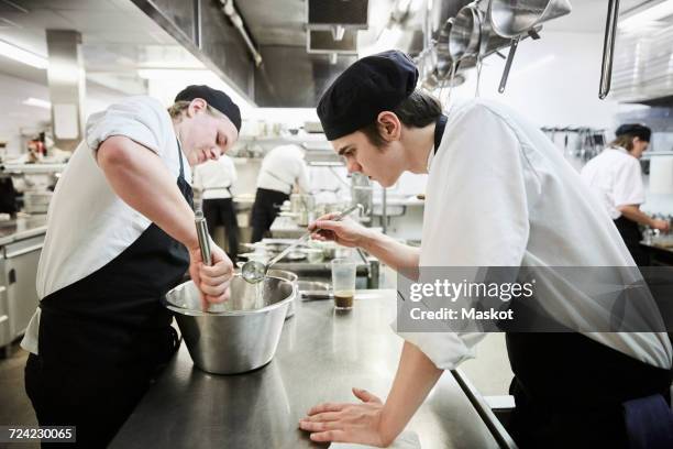 side view of male chef students making food in commercial kitchen - servierbesteck stock-fotos und bilder