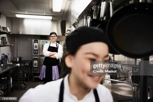 portrait of confident male chef with colleague in foreground at commercial kitchen - kochlehrling stock-fotos und bilder