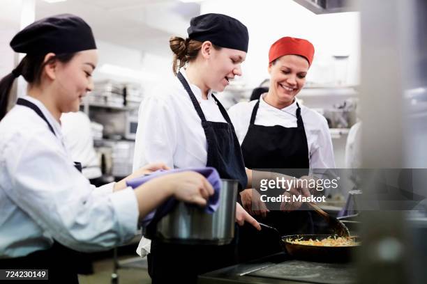 teacher watching female chef students cooking food in commercial kitchen - kochlehrling stock-fotos und bilder